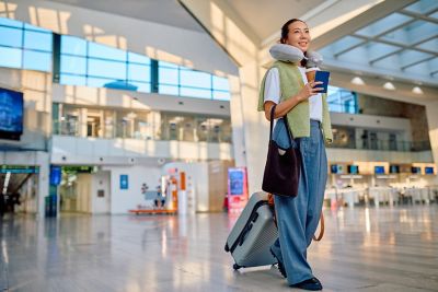A comfortably dressed traveller with a neck cushion ahead of a long-haul flight