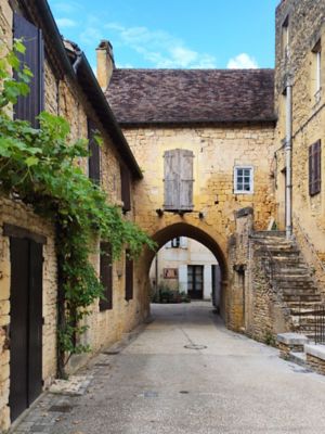 Rue pavée sous une arche de pierre dans le village médiéval de Cadouin, en Dordogne