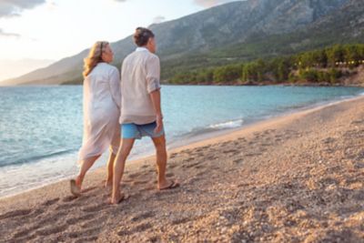 A couple enjoying a golden-hour stroll on a sandy Mediterranean shore