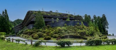 Edificio brutalista del Hotel Monte Palace abandonado, rodeado de vegetación junto a la carretera