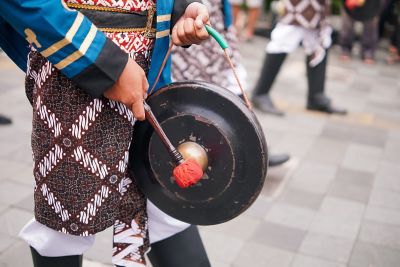A traditional Javanese gong player at an outdoor ceremony in Indonesia