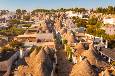 Toits coniques et maisons blanches du village d’Alberobello, à la lueur orangée du coucher du soleil