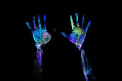Hands illuminated by ultra-violet light, like at Prague's Image Black Light Theatre