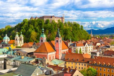 Hilltop Ljubljana Castle overlooking the city's rooftops against a blue sky