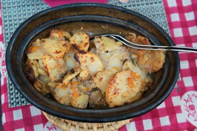 Guiso tradicional de patatas y carne en cazuela de barro sobre mantel de cuadros rojos