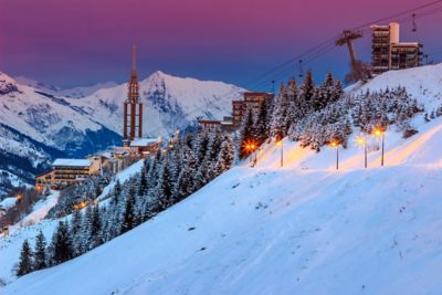 A beautiful pink sunrise over the chalets and slopes of Les Menuires ski resort in France