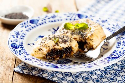 Mit Pflaumenmus gefüllte und mit Mohn bestreute Germknödel auf blau-weißem Teller