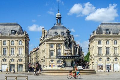 Femme traversant la place de la Bourse à vélo