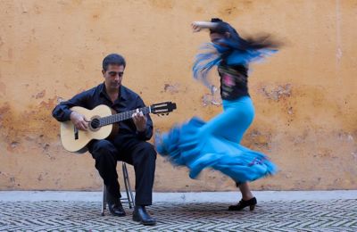 A flamenco dancer twirling as a guitarist plays on a street in Spain