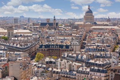 Panorámica urbana de París con edificios clásicos, iglesias y el Panteón bajo un cielo nublado