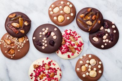 Elegant drapierte, mit Schokoladenglasur und verschiedenen Garnierungen verzierte Kekse