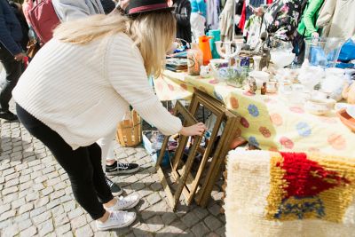 Femme qui regarde des cadres posés devant un étal de brocante