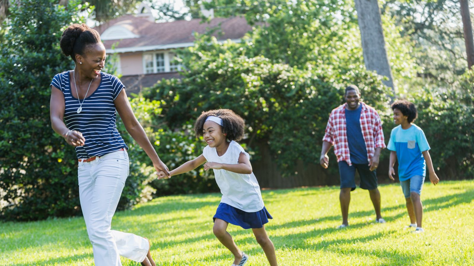 A family laughing and playing in a park in the summer sun