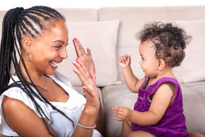 A parent and baby laughing as they play a simple family game with their hands