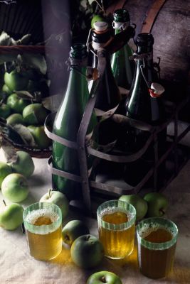 Verres de cidre, pommes vertes et bouteilles de cidre sur une table