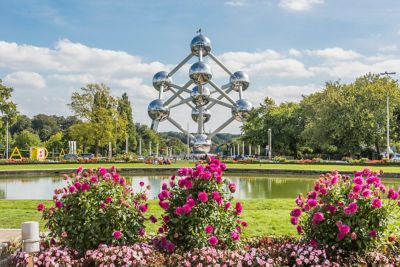 Das Atomium in Brüssel an einem sonnigen Tag, mit Blumen und Grünanlage im Vordergrund