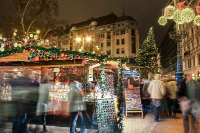 Mercado navideño nocturno en Budapest con luces, puestos y gente desenfocada
