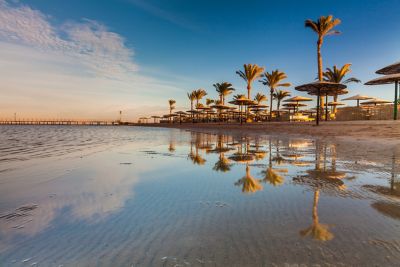 Sonnenuntergang am Strand von Hurghada mit Palmen, die sich im Meer spiegeln