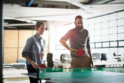 Deux collègues jouent en équipe au ping-pong durant leur temps de repos entre deux sessions de travail