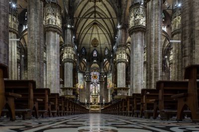 The nave of Milan Cathedral, with a vaulted ceiling, impressive columns and stained glass