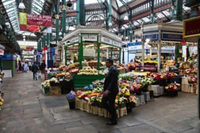 Colourful fruit and vibrant flower bouquets lining stalls in Kirkgate Market in Leeds