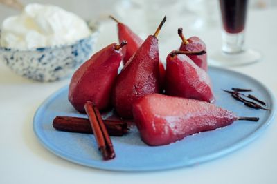 Primer plano de peras al vino, decoradas con ramas de canela