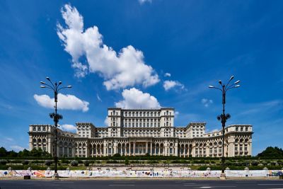 Fachada del colosal Palacio del Parlamento de Bucarest bajo un cielo azul con nubes blancas