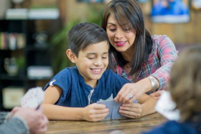 A parent helping a child during a family game of cards