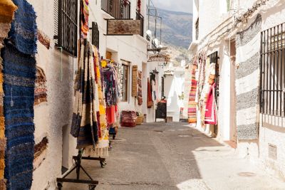 Callejón con casas blancas y bufandas coloridas colgando en un pueblo de la Alpujarra.