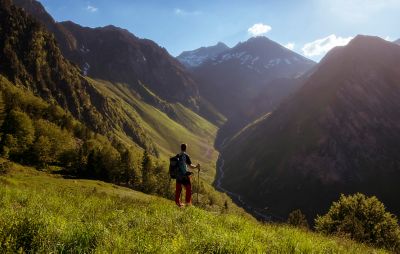 A hiker gazing into a river valley amid grassy mountains in the French Pyrenees