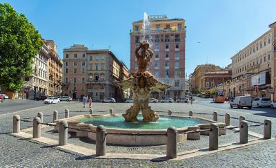 Fontana del Tritone, showing Triton and dolphins, in lively Piazza Barberini in Rome, Italy