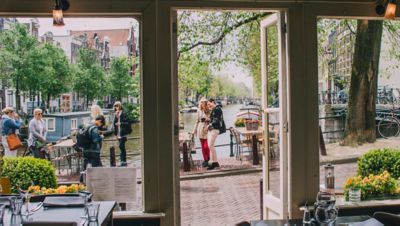Passants et visiteurs qui discutent, à l’entrée d’un café à Amsterdam
