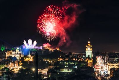 Buntes Feuerwerk über dem nächtlichen Edinburgh mit erleuchteter Princes Street