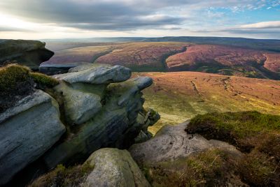 Boulders overhanging dramatic heather moorland in the Peak District, Derbyshire