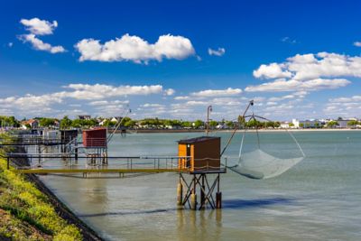Cabanes de pêcheurs et filets de pêche suspendus à Saint-Nazaire, sous un ciel bleu et quelques nuages
