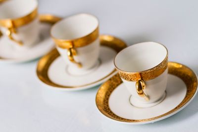 Trois tasses en porcelaine avec ornement doré, sur une table blanche