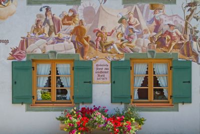 Windows with green shutters and the painted exterior wall of a house in Mittenwald village near Munich