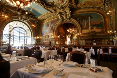The gilded, frescoed interior of a fine dining French restaurant in Paris