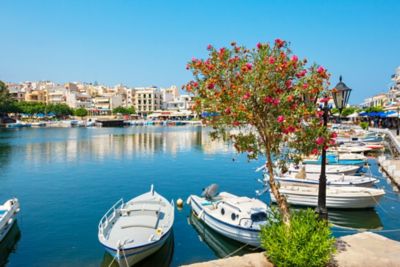 Kleine blauweiße Boote liegen vertäut am Ufer des Voulismeni-Sees auf Kreta