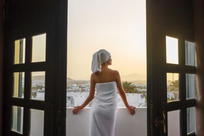 A towel-clad traveller enjoying the morning sun on a hotel balcony in the mountains
