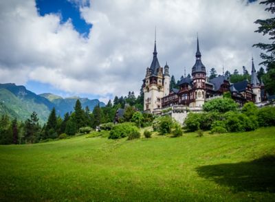 Turreted Peleș Castle on a slope in an alpine forest