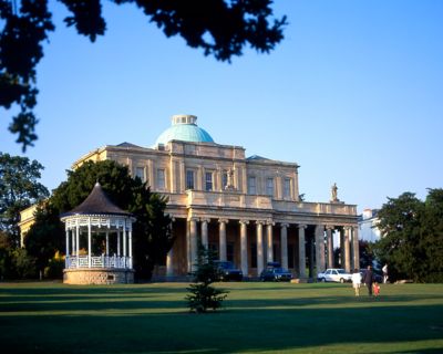 The colonnaded, domed Pittville Pump Room facing a grassy lawn in Cheltenham