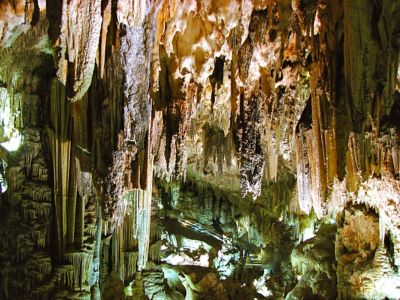 Interior de la cueva con estalactitas y estalagmitas iluminadas.