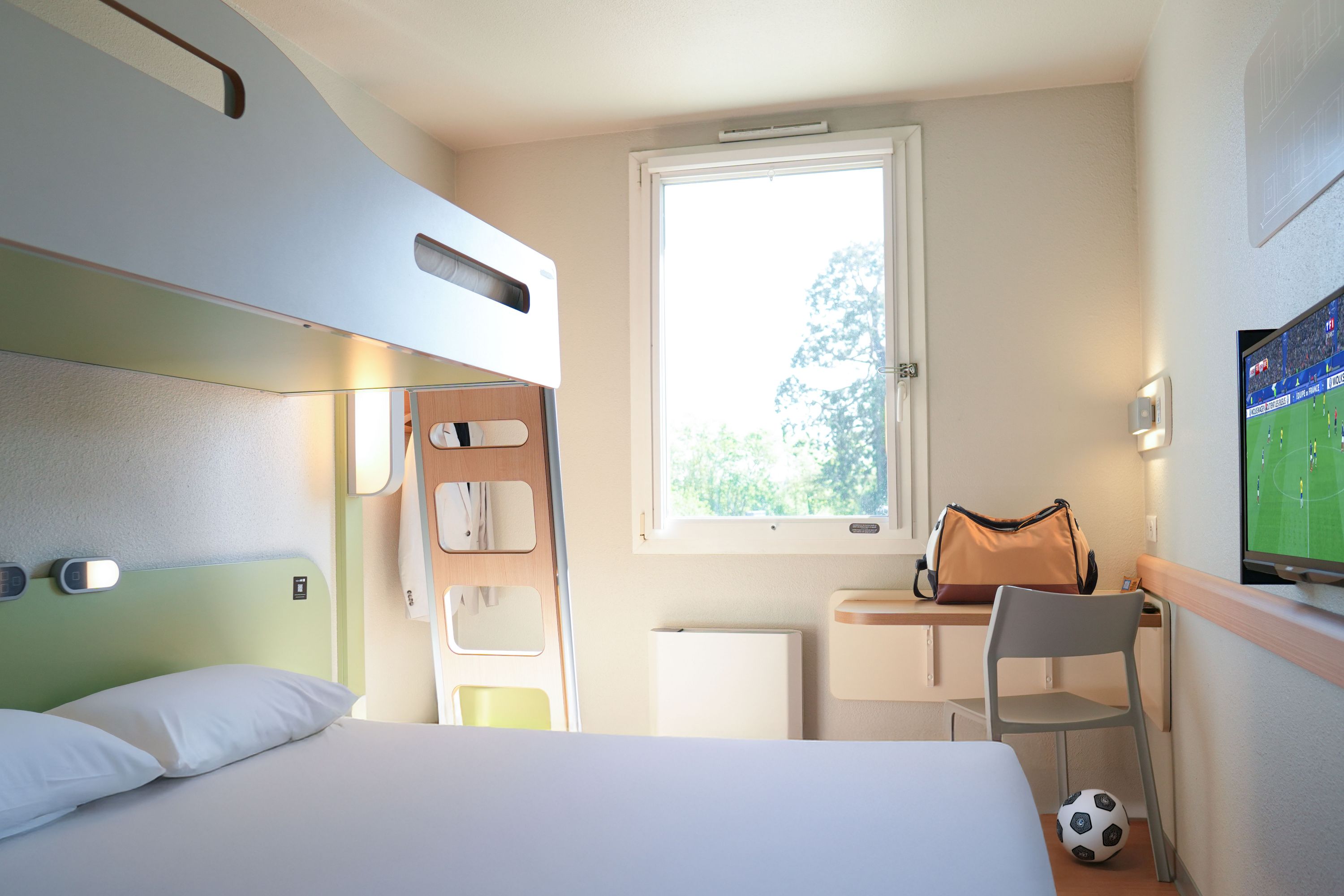 Modern Hotel Room with Bunk Bed and Soccer on TV