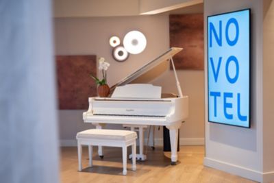 Un piano blanc est à disposition des visiteurs dans le lobby d'un hôtel Novotel en France