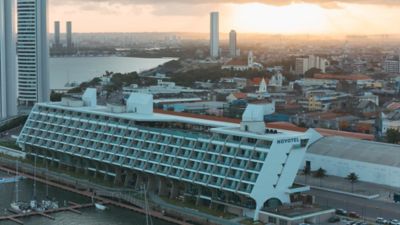 Sunset over a cityscape featuring a modern Novotel hotel