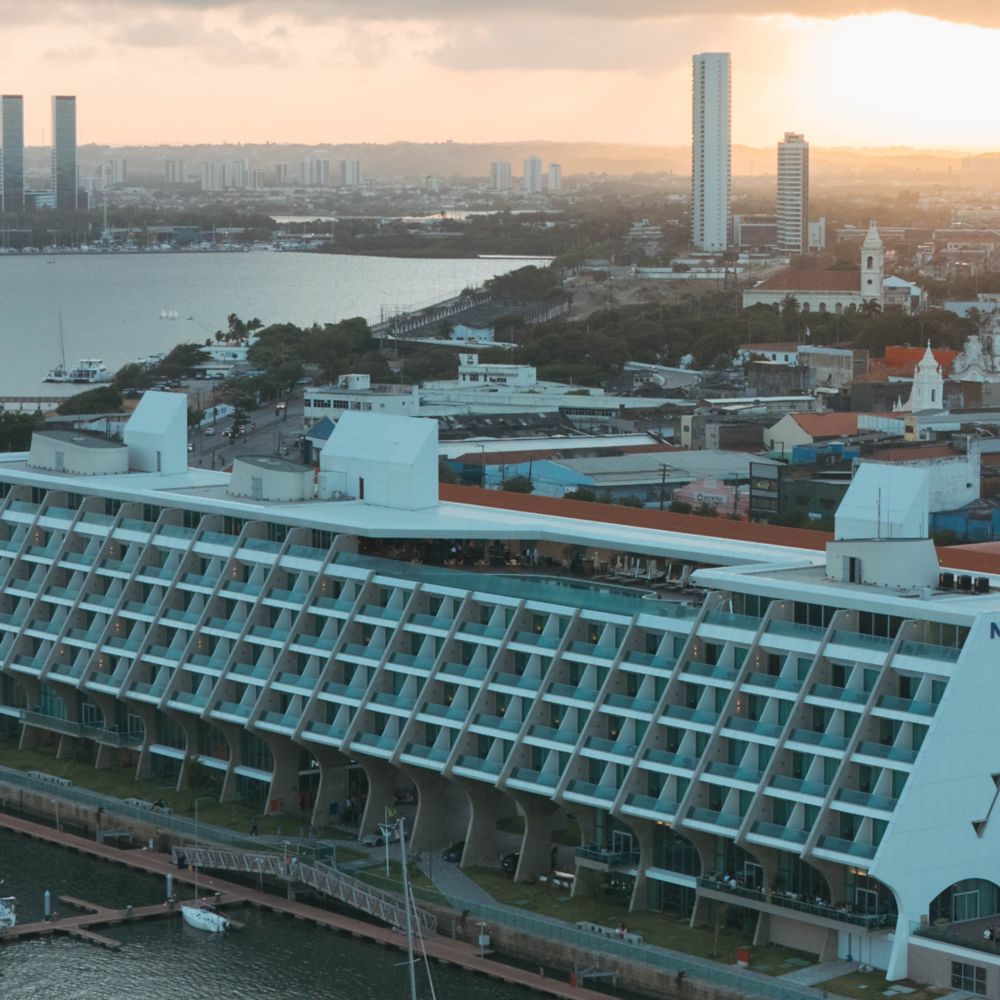 Sunset over a cityscape featuring a modern Novotel hotel