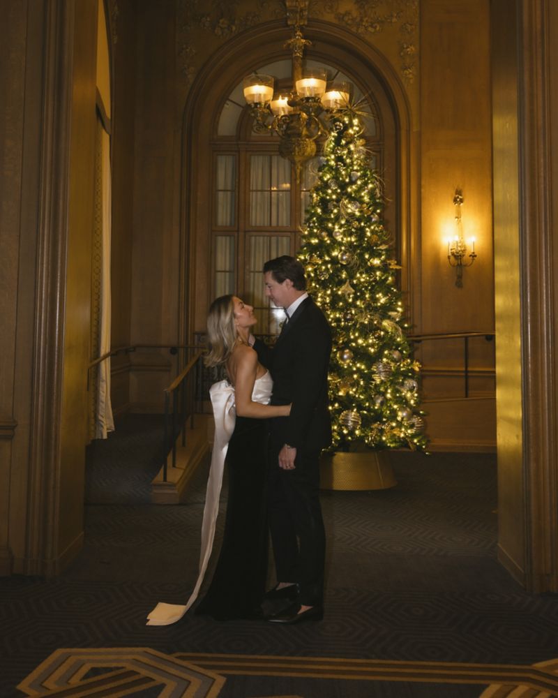 A couple posing in front of a christmas tree