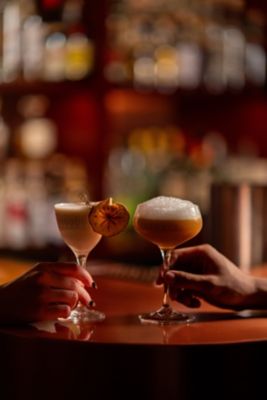 two hands holding cocktails