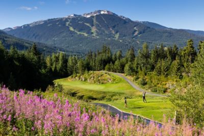 Two golfers playing at Fairmont Chateau Whistler Golf Club with mountain views